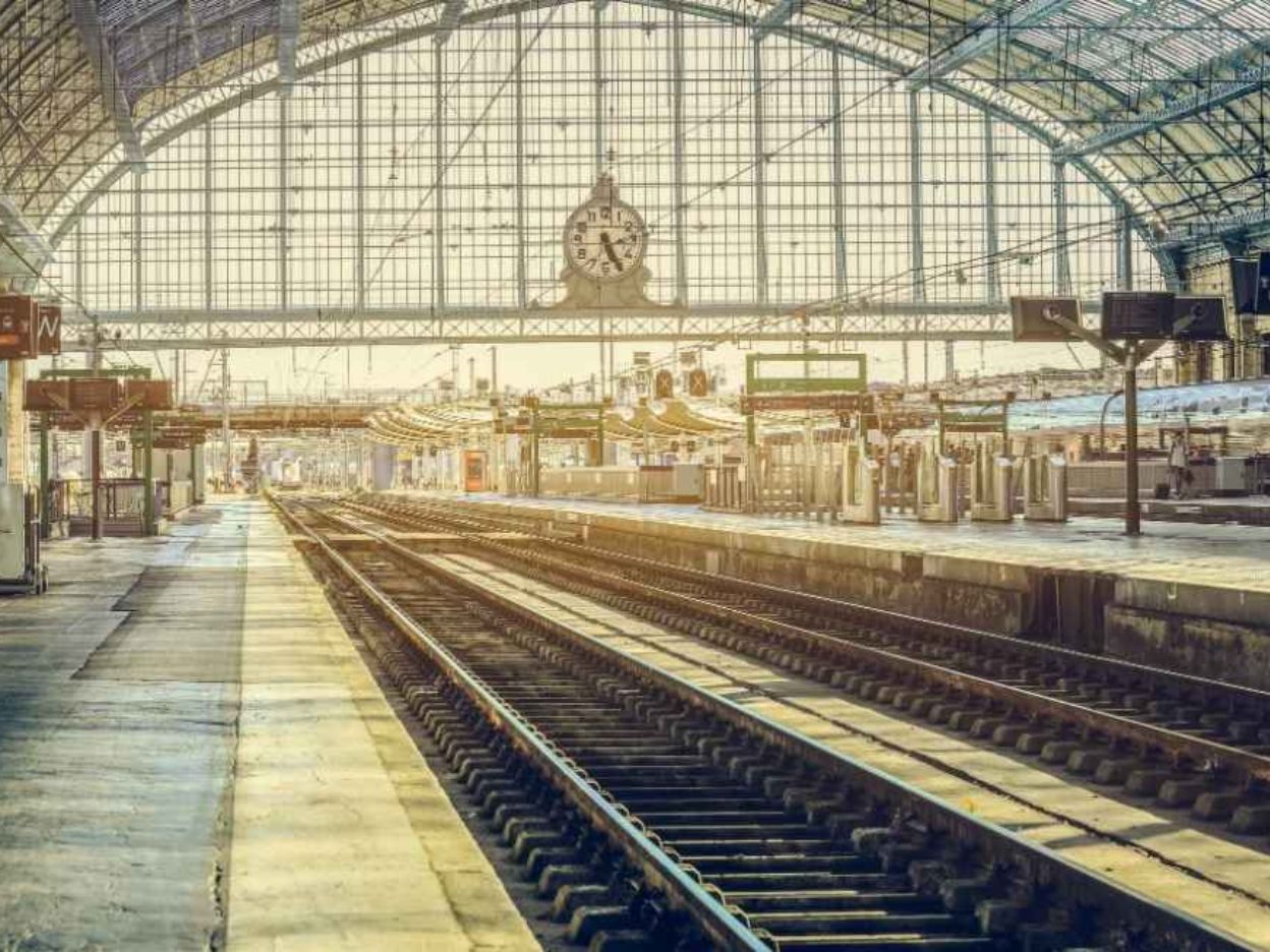 Intérieur moderne de la Gare de Bordeaux Saint-Jean avec des voyageurs, des écrans d'information et une architecture lumineuse